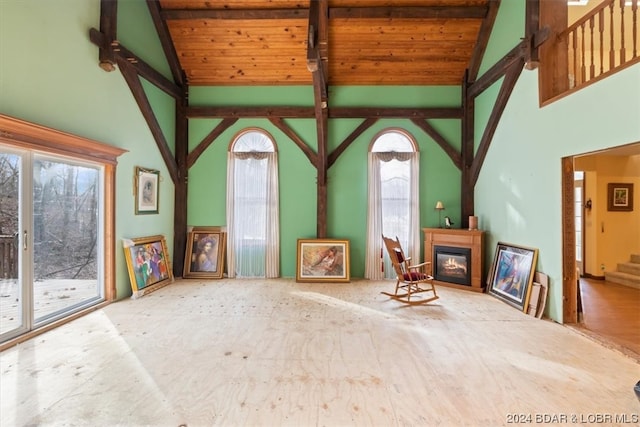 unfurnished living room with light wood-type flooring, a wealth of natural light, beamed ceiling, and wooden ceiling