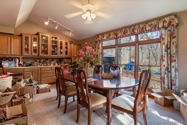 carpeted dining space with ceiling fan, lofted ceiling, indoor bar, and track lighting