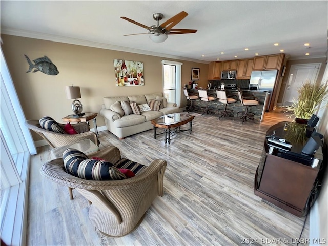 living room with ceiling fan, crown molding, and light hardwood / wood-style flooring