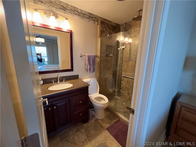 bathroom with toilet, an enclosed shower, vanity, and a textured ceiling