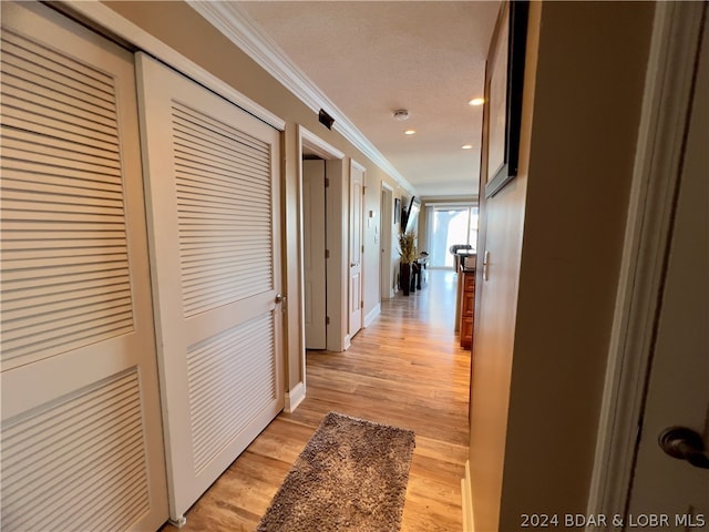 hallway with a textured ceiling, light hardwood / wood-style floors, and crown molding