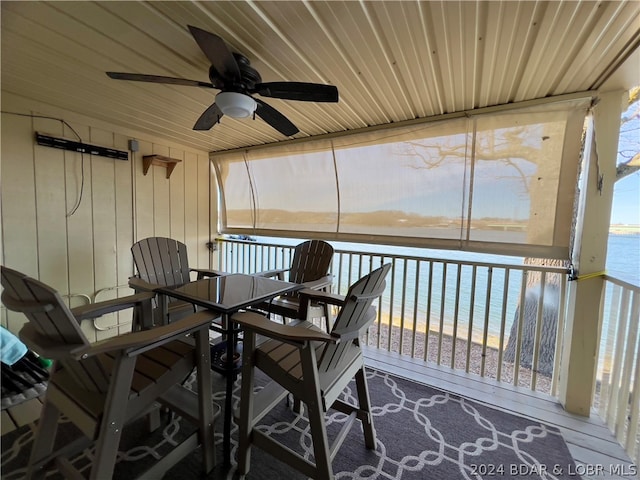 sunroom / solarium featuring ceiling fan, a water view, wooden ceiling, and a view of the beach