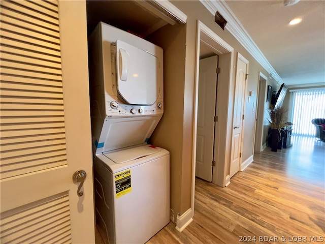 clothes washing area with stacked washer and clothes dryer, crown molding, and light hardwood / wood-style flooring