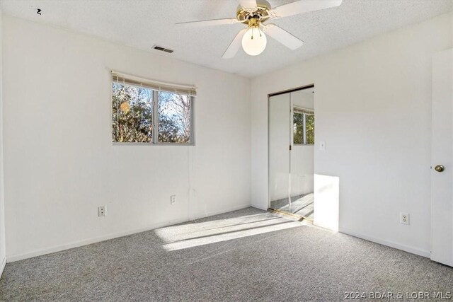 spare room featuring carpet flooring, ceiling fan, a healthy amount of sunlight, and a textured ceiling