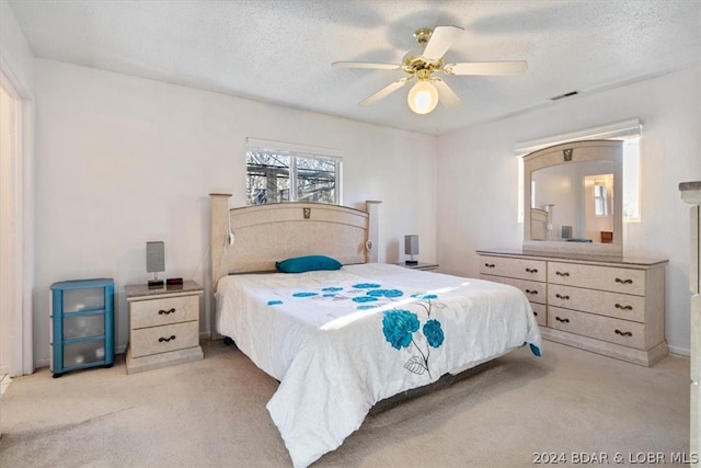 bedroom featuring a textured ceiling, light colored carpet, and ceiling fan