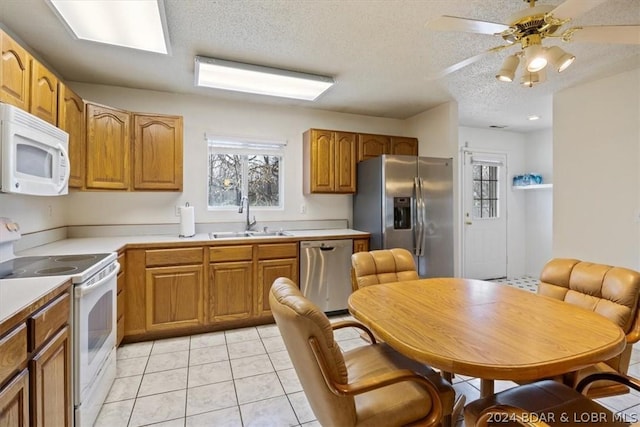 kitchen featuring sink, ceiling fan, light tile patterned floors, a textured ceiling, and appliances with stainless steel finishes