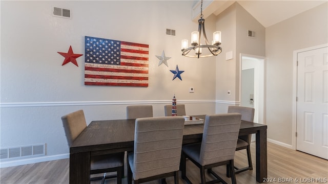 dining room with high vaulted ceiling, light hardwood / wood-style floors, and an inviting chandelier