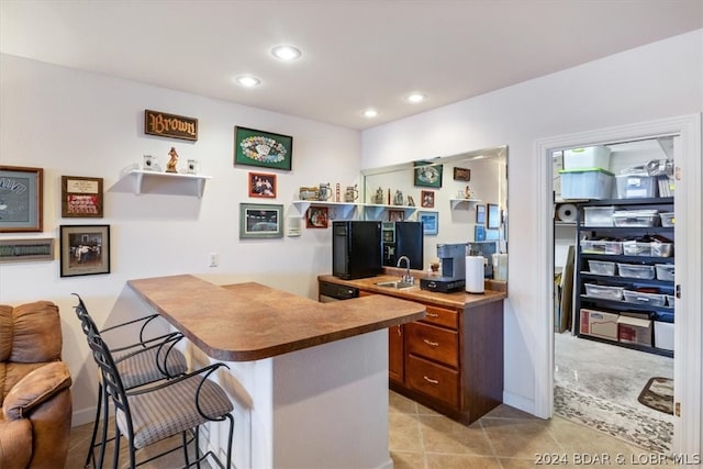 kitchen with light tile floors, kitchen peninsula, sink, and a breakfast bar