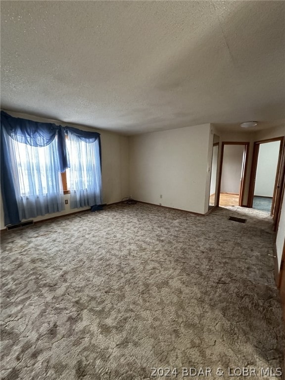 spare room featuring carpet flooring and a textured ceiling