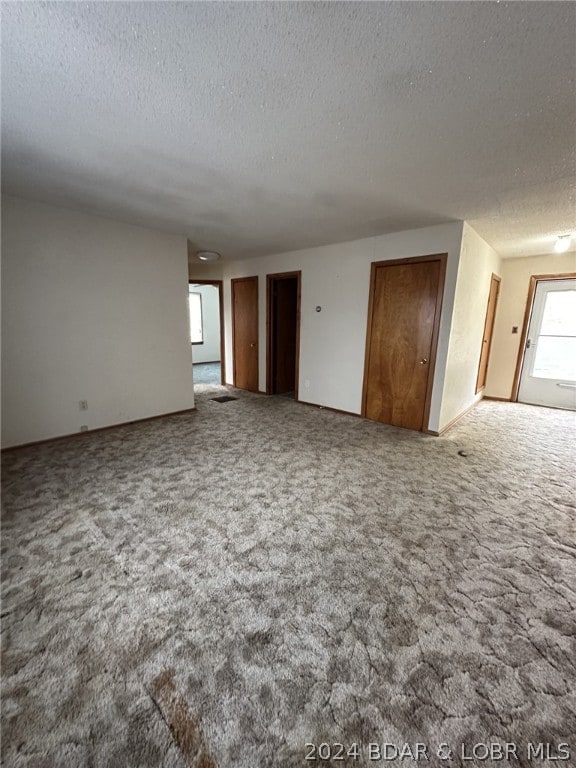 carpeted spare room with a textured ceiling