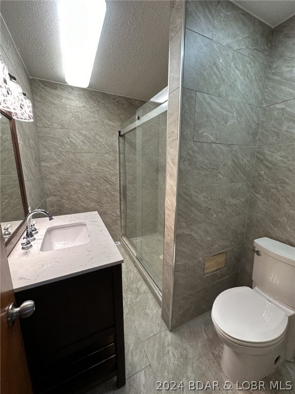 bathroom with walk in shower, tile floors, tile walls, vanity, and toilet