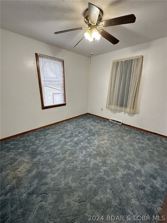 carpeted empty room with a textured ceiling and ceiling fan