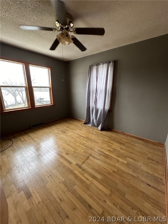 empty room featuring ceiling fan, light hardwood / wood-style floors, and a textured ceiling