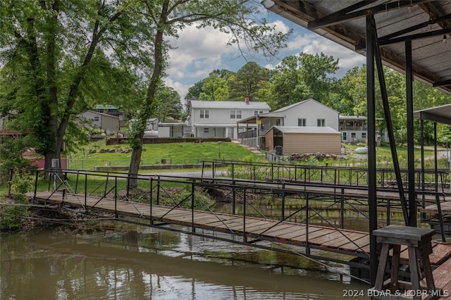 view of dock with a water view and a yard