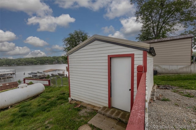 view of shed / structure with a lawn and a water view