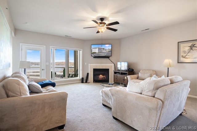 living room with a fireplace, light colored carpet, and ceiling fan