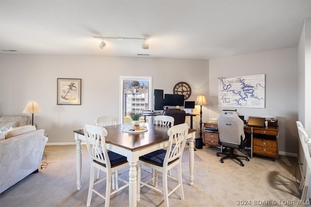 dining area featuring light carpet and track lighting