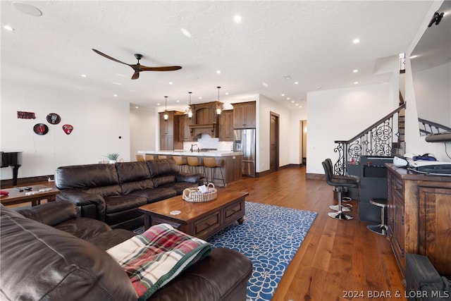 living room with ceiling fan, sink, and dark wood-type flooring