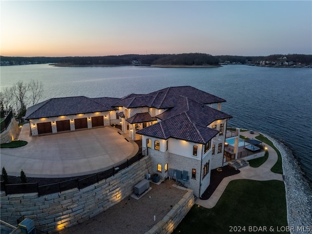 aerial view at dusk featuring a water view