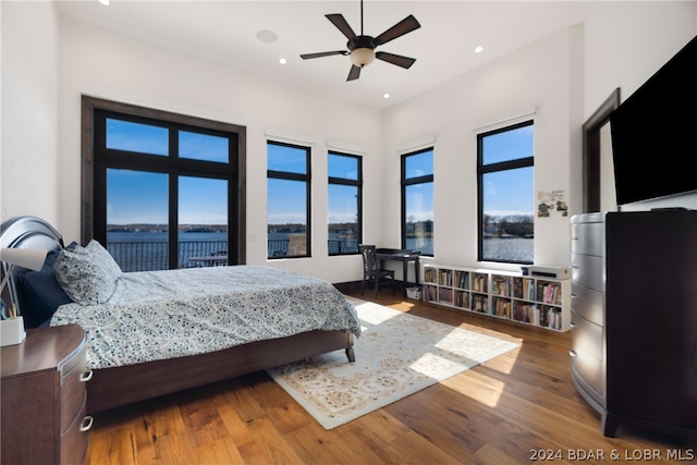 bedroom featuring a water view, wood-type flooring, ceiling fan, and access to outside