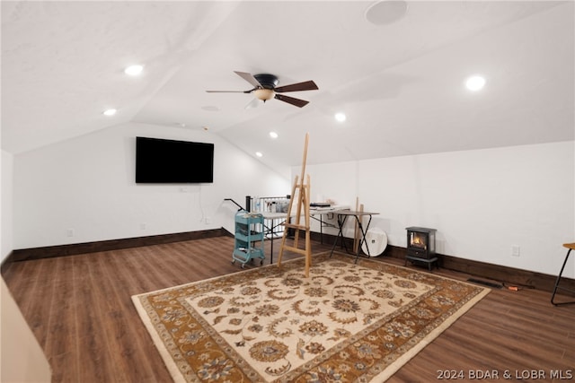 sitting room featuring dark hardwood / wood-style flooring, ceiling fan, lofted ceiling, and a wood stove