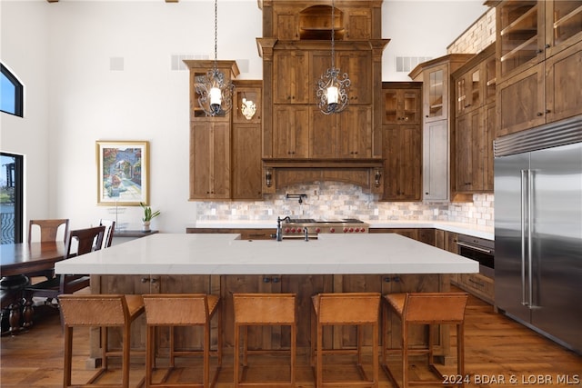 kitchen with a kitchen breakfast bar, pendant lighting, a center island with sink, and built in fridge