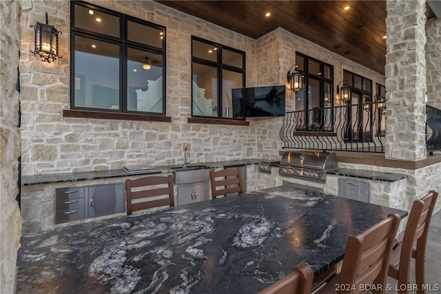 kitchen with wood ceiling, dark stone counters, and sink