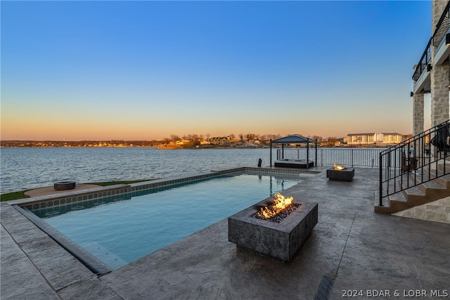 pool at dusk featuring a patio, an outdoor fire pit, and a gazebo