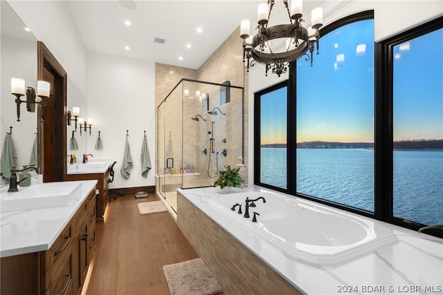 bathroom with wood-type flooring, a water view, vanity, and separate shower and tub