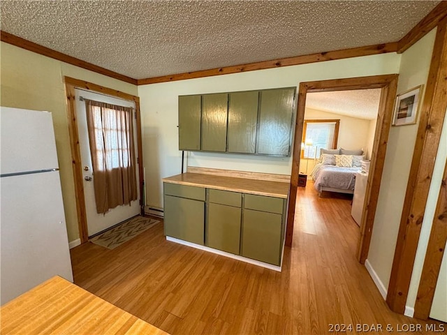 kitchen featuring a textured ceiling, white refrigerator, light hardwood / wood-style floors, and green cabinetry