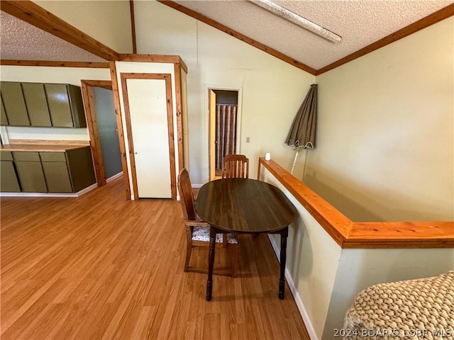 hall with lofted ceiling, light wood-type flooring, and a textured ceiling