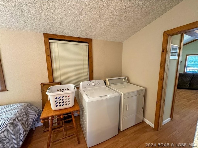 clothes washing area with a textured ceiling, independent washer and dryer, and hardwood / wood-style flooring