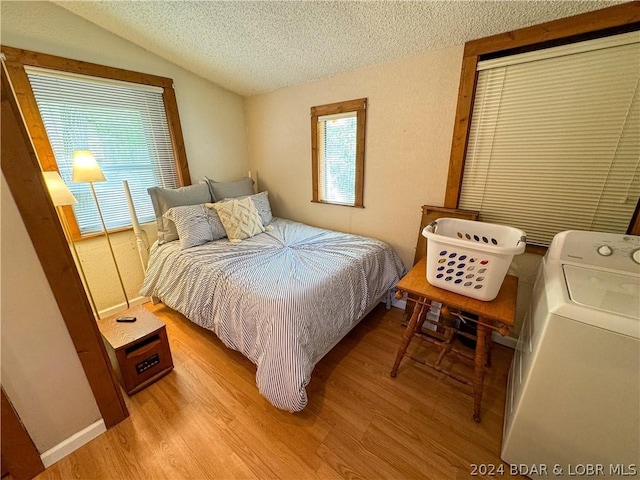 bedroom featuring a textured ceiling, washer / dryer, lofted ceiling, and light wood-type flooring