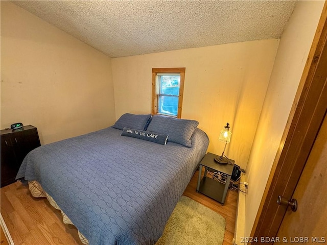 bedroom with hardwood / wood-style floors and a textured ceiling