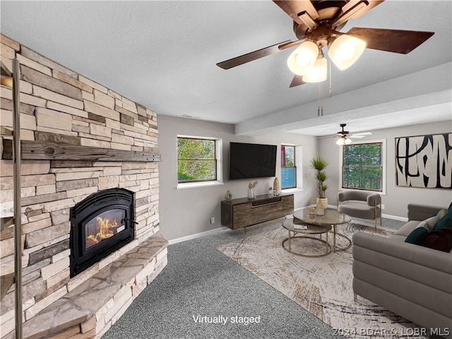 carpeted living room featuring a fireplace, ceiling fan, and a textured ceiling