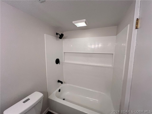 bathroom with tiled shower / bath combo, a textured ceiling, and toilet