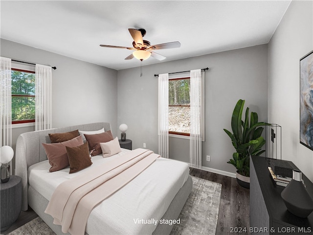 bedroom featuring ceiling fan, dark hardwood / wood-style flooring, and multiple windows