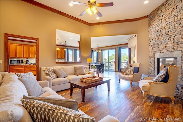 living room featuring crown molding, a fireplace, dark hardwood / wood-style flooring, and ceiling fan with notable chandelier