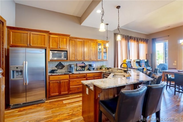 kitchen with sink, hanging light fixtures, stainless steel appliances, a kitchen bar, and kitchen peninsula