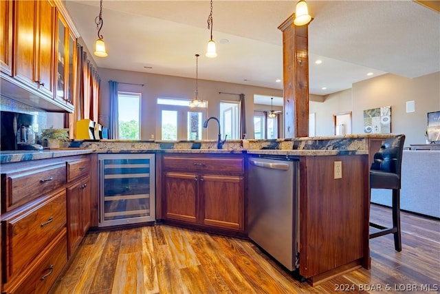 kitchen with wine cooler, a breakfast bar, hanging light fixtures, stainless steel dishwasher, and hardwood / wood-style flooring