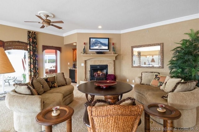 living room featuring ceiling fan, ornamental molding, and a tile fireplace