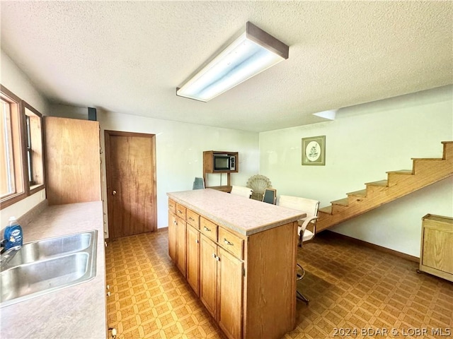 kitchen featuring built in microwave, a center island, sink, a textured ceiling, and a breakfast bar area