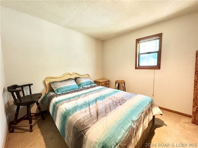 bedroom featuring light colored carpet and a textured ceiling