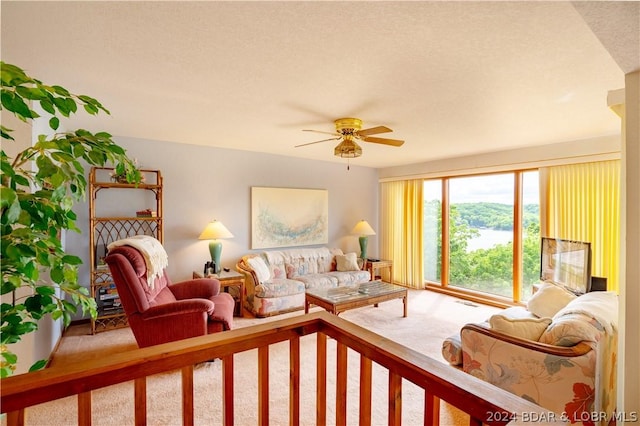 carpeted living room featuring ceiling fan and a textured ceiling