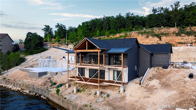 rear view of house with a patio, a balcony, and a water view