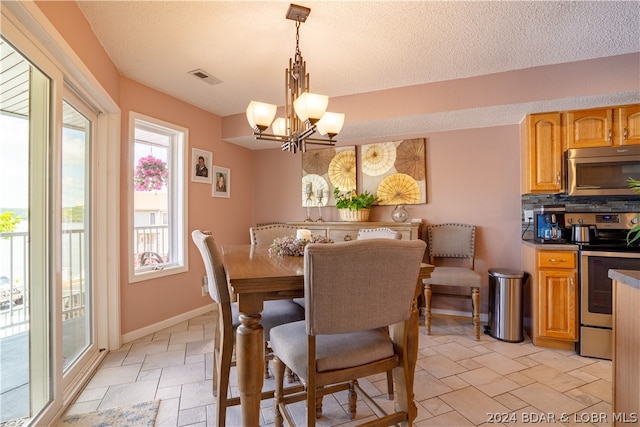 dining area with a healthy amount of sunlight, a textured ceiling, and a notable chandelier