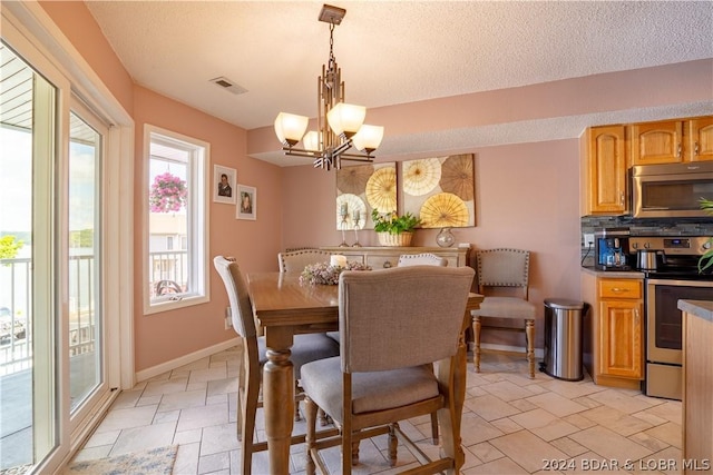 dining room featuring visible vents, a textured ceiling, stone tile floors, baseboards, and a chandelier