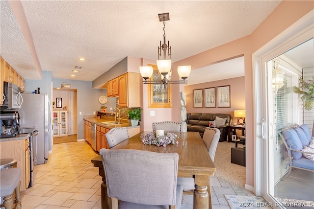 dining space featuring sink, a chandelier, and a textured ceiling