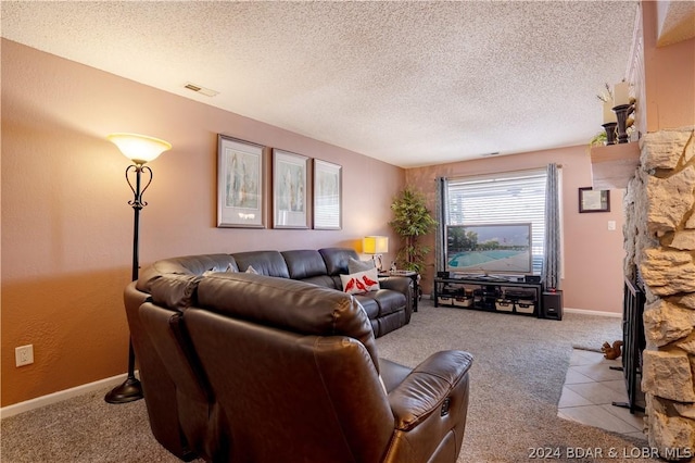 carpeted living area with a stone fireplace, baseboards, visible vents, and a textured ceiling