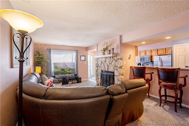 living room with a stone fireplace, light colored carpet, and a textured ceiling